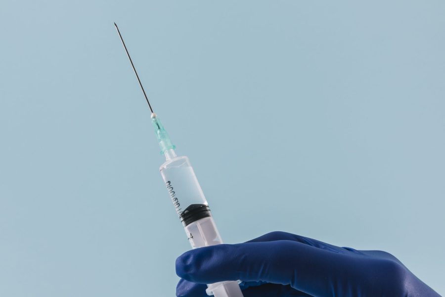 close-up-doctor-hand-with-syringe-blue-backdrop