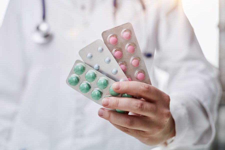 Pharmacological therapy. Close up portrait female doctor scientist pharmacist looking at camera presenting new effective pill medicine. Focus on yellow capsule in woman medical worker hand