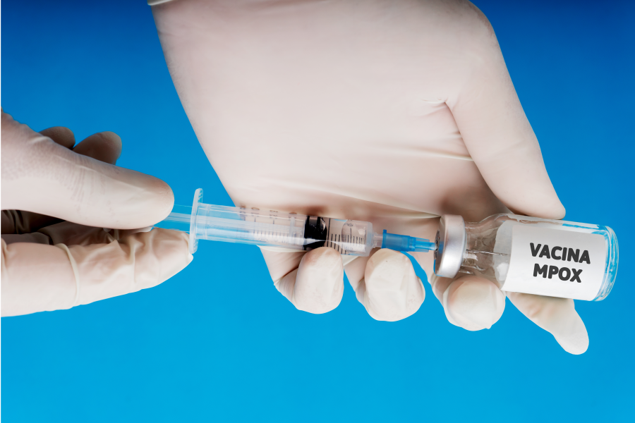 cropped-hand-person-holding-vial-with-syringe-against-blue-background