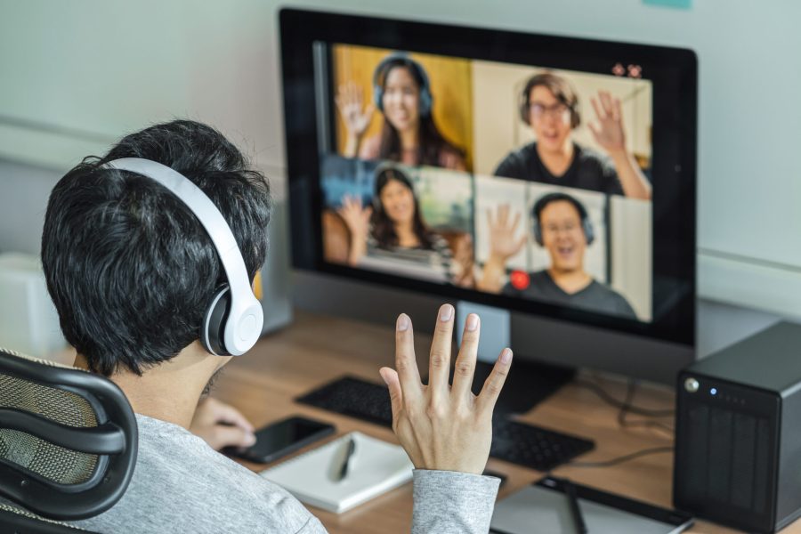 Rear View of Asian Business man say hello with teamwork colleague in video conference when Coronavirus outbreak, Covid-19 pandemic, online meeting, Social distancing and new normal concept